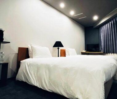 Twin beds with white linens, bedside lamp and kettle on shelf in Hotel & Onsen 2307 Shigakogen room, Nagano