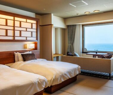 Twin beds on tatami platform with sofa and sea view at Hotel Oosado Niigata