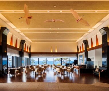 Spacious wooden-floored lobby with low lounge seating and floor-to-ceiling windows overlooking a coastal view at Hotel Oosado, Niigata