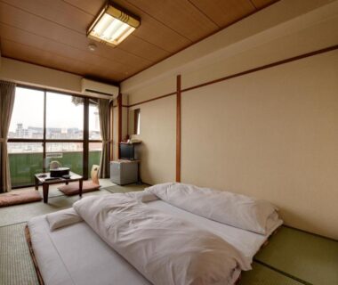 Tatami room with futons, low table and balcony overlooking Kyoto at Hotel Oumiya