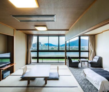 Tatami seating area with low table, bed and large windows overlooking mountains at Hotel Park, Gifu, Chūbu