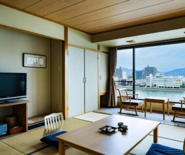 Tatami room with low table, floor cushions and river view at Hotel Park in Gifu