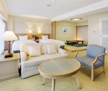 Spacious mixed Western and Japanese room with twin beds, sofa, table and tatami area at Hotel Resorpia Atami in Shizuoka