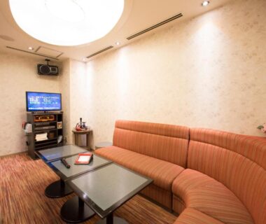 Curved orange sofa, low tables and TV in a lounge at Hotel Resorpia Atami, Shizuoka