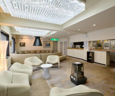 Spacious hotel lounge with curved sofas, central table, chandelier lighting and reception area at Hotel ST MORITZ, Niigata