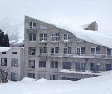 Snow-covered exterior of Hotel ST MORITZ with mountains in Niigata