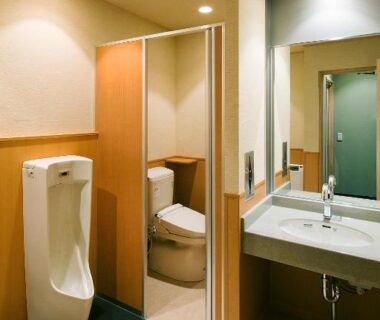 Clean restroom with urinal, toilet stall, sink and mirror at Hotel Saginoyu in Nagano