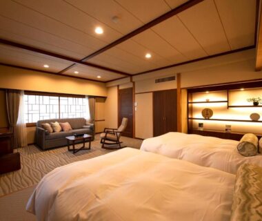 Japanese-style room with twin beds, seating area and shoji window at Hotel Saginoyu in Nagano