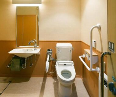 Accessible toilet with handrails and sink at Hotel Saginoyu, Nagano