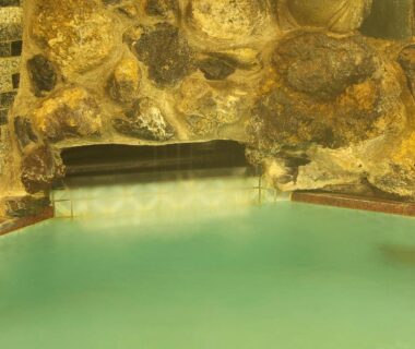 Indoor rock-lined onsen bath with milky turquoise water