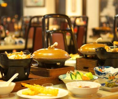 Japanese multi-course table with individual hot pots, tempura and small ceramic dishes in ryokan dining room