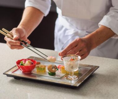 Chef arranging small appetizers on a lacquer tray at Hotel Sanrakuso in Wakayama, Kansai