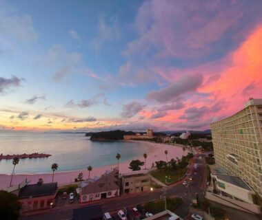 Vibrant pink sunset over Wakayama bay with Hotel Sanrakuso building, coastline road and calm water