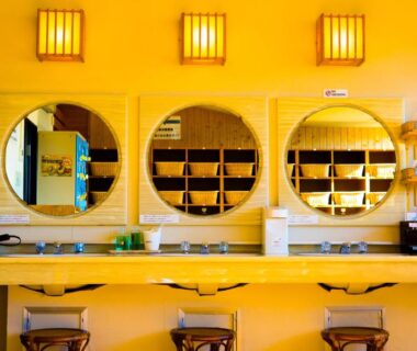 Three round mirrors above a wooden counter with stools and shelving in a ryokan wash area at Hotel Sekitei, Yamanashi