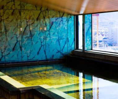 Marble-lined indoor bath with large window city view at Hotel Sekitei in Yamanashi prefecture