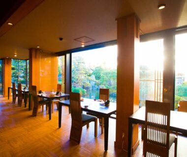 Sunlit dining room with wooden tables and garden view at Hotel Sekitei Yamanashi