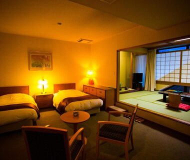 Tatami seating with low table and shoji, adjacent twin beds and chairs at Hotel Sekitei in Yamanashi