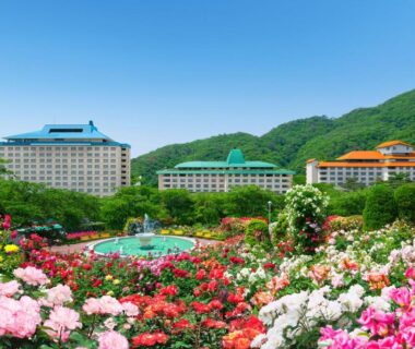 Colorful rose garden and fountain before Hotel Senshukaku with verdant hills in Tōhoku