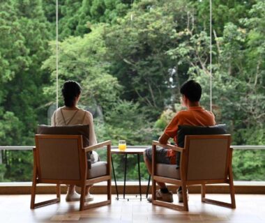 Two guests seated on open wooden veranda overlooking lush forest at Hotel Shidotaira, Iwate Tōhoku