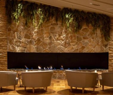 Warm lobby lounge with stone wall and linear fireplace, armchairs facing fire at Hotel Shidotaira, Iwate, Tōhoku