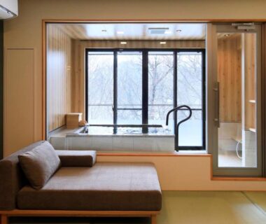 Tatami room with low sofa and wooden soaking tub beside large window at Hotel Shikisai Tochigi