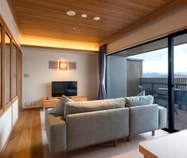 Sofa lounge with balcony and distant mountain setting at Hotel Shion, Iwate
