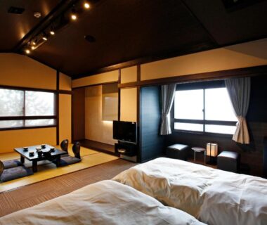 Tatami room with futon beds, low table, shoji screens and window at Hotel Shosenkaku Romankan, Kumamoto