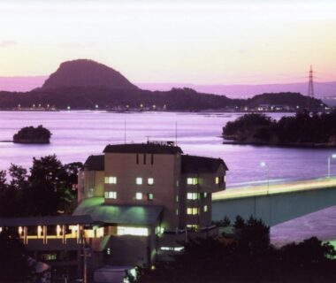Twilight bay with bridge and illuminated ryokan Hotel Shosenkaku Romankan in Kumamoto Kyushu