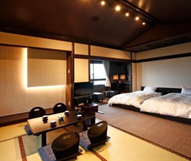 Spacious tatami room with low table, floor chairs and two beds at Hotel Shosenkaku Romankan in Kumamoto