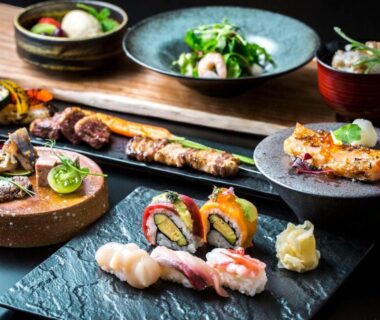 Assorted sushi, nigiri, rolled sushi and grilled fish on ceramic plates in a ryokan dining setting