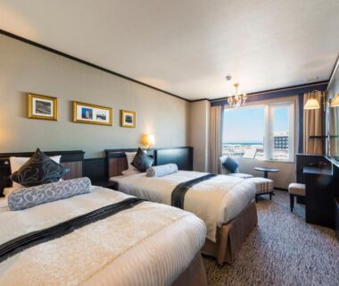 Three single beds with bedside lamps and seating area at Hotel Sonia Otaru Hokkaidō