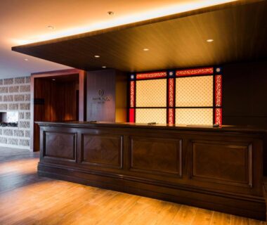 Warm-lit hotel lobby reception with wooden counter and decorative panels at Hotel Sonia Otaru Hokkaidō