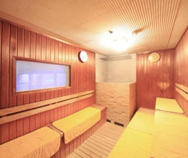 Interior wooden sauna with bench seating and small window at Hotel Sun Hatoya in Shizuoka