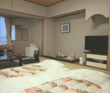 Traditional tatami room with two futons, low table, TV and kettle at Hotel Sun Hatoya, Shizuoka