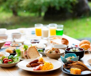 Assorted Japanese and Western breakfast dishes and juices on table with garden view at Hotel Sunvalley Izunagaoka