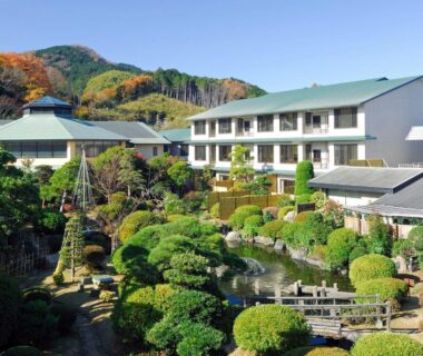Landscaped Japanese garden with pond, stone lantern and trimmed shrubs in front of the ryokan in Shizuoka