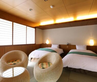 Tatami room with twin beds, shoji screens and wicker chairs at Hotel Tamanoyu in Nagano