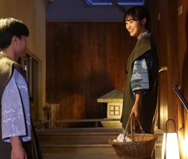 Two guests in yukata holding a basket on lantern-lit wooden stairs at Hotel Tamanoyu in Nagano