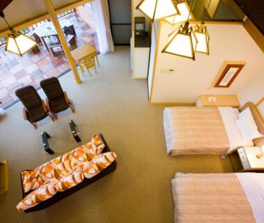 Twin beds with sofa and lounge chairs by large window at Hotel Tenzankaku Kaiyutei, Wakayama