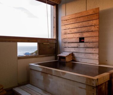 Indoor wooden soaking tub with sea view at Hotel Tenzankaku Kaiyutei in Wakayama