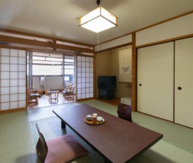 Tatami room with low table, shoji screens and seating area at Hotel Tenzankaku Kaiyutei in Wakayama