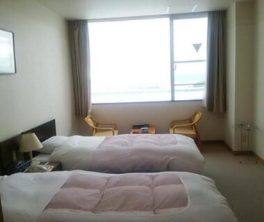 Twin beds and window seating at Hotel Tetora Resort Tsuruoka in Yamagata