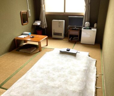 Tatami room with futon, low table, heater and small fridge at Hotel Tetora Yunokawaonsen, Hokkaidō, Japan