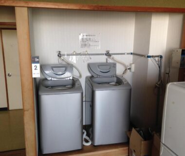 Two top-loading laundry machines in a small utility alcove at Hotel Tetora Yunokawaonsen Hokkaidō