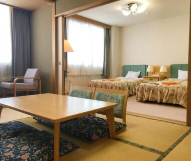 Tatami mat room with low table, cushions and adjacent twin beds at Hotel Tetoraresort Tokachigawa in Hokkaidō