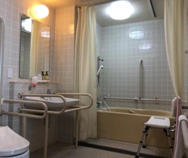 Tiled accessible bathroom with bathtub, shower stool and grab bars at Hotel Tetoraresort Tokachigawa Hokkaido