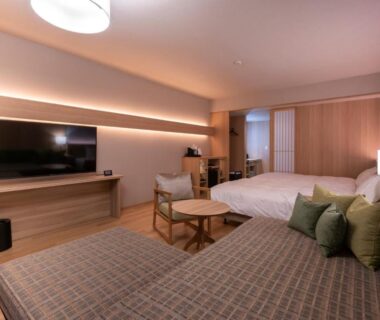 Spacious room with bed, sofa, low table, TV and wooden flooring at Hotel Tokinoza in Mie, Kansai, Japan