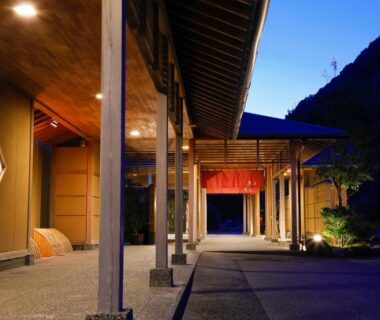 Covered walkway with wooden columns and red noren at Hotel Tokinoza entrance in Mie