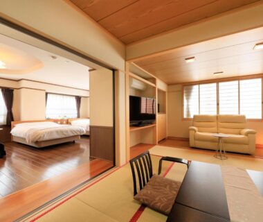 Ryokan room with tatami seating, low table, western beds and sofa at Hotel Tsubakino Nagano