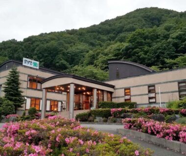 Hotel Uguisu entrance with pink flower beds and forested hillside in Iwate